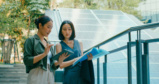 Two women reviewing solar system documents in front of residential solar panels